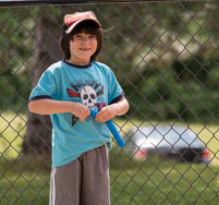 little boy with a baseball hat on, playing outside